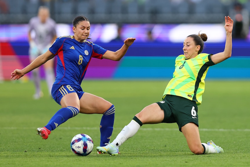 Matildas player Clare Wheeler lunges for the ball, as a Philippines player approaches