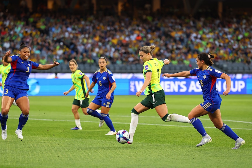Matildas player Steph Catley prepares to kick the ball during a game, she has three Philippines defenders around her