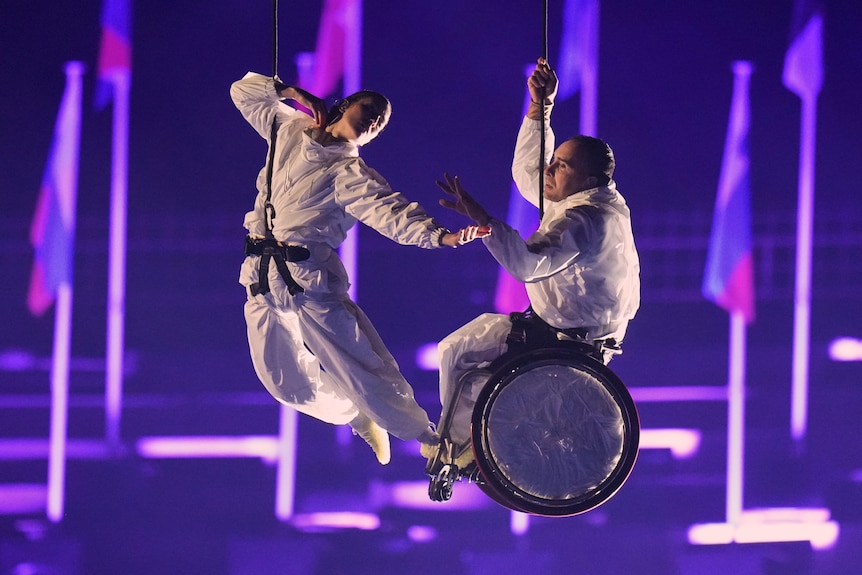 Two performers suspended in midair during the 2026 Winter Paralympics opening ceremony.