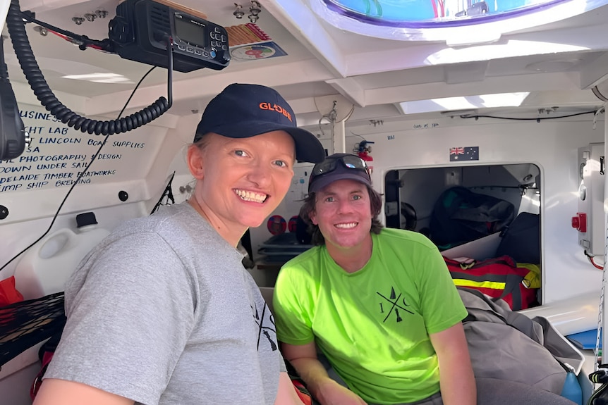 Dan Turner in a green t-shirt and his wife, Nikki Turner, in a grey t-shirt and black hat, smile below deck.