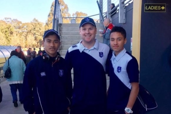 Two boys pose for a photo with a rugby league coach 