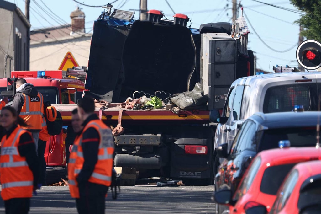 Firefighters stand on a road after the collision between a TGV train and a truck. Photo: AFP