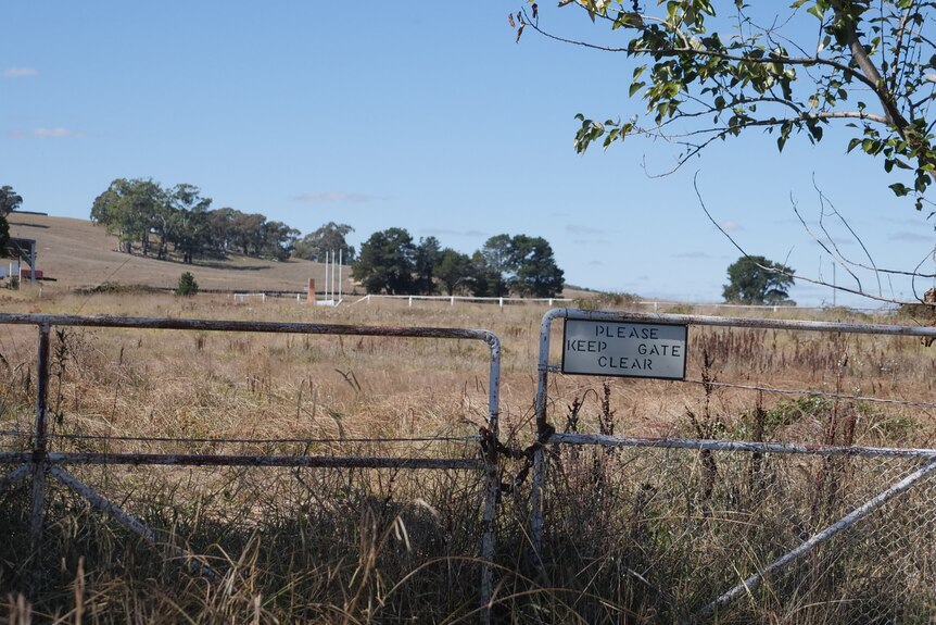picture of gate in foreground and old horse racing tack in paddock