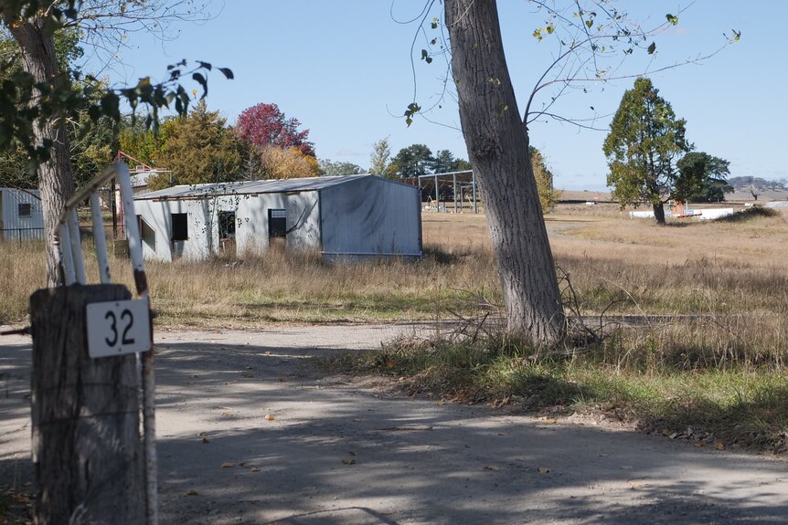 picture of sheds in field with 32 on fence in foreground