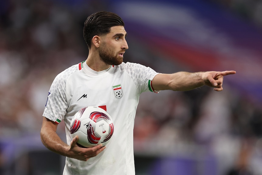 Alireza Jahanbakhsh points while holding a football in his right hand