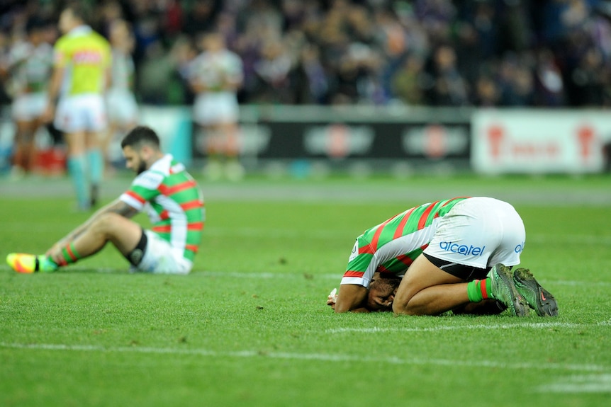 Two men slump on the turf after losing a rugby league match 
