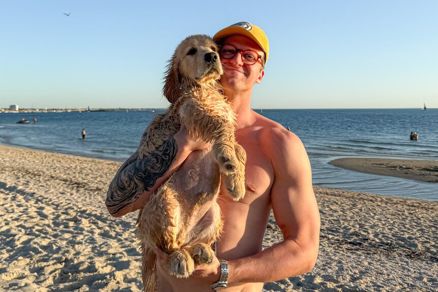 Sam Williamson carries his dog, a golden retriever on his shoulder.