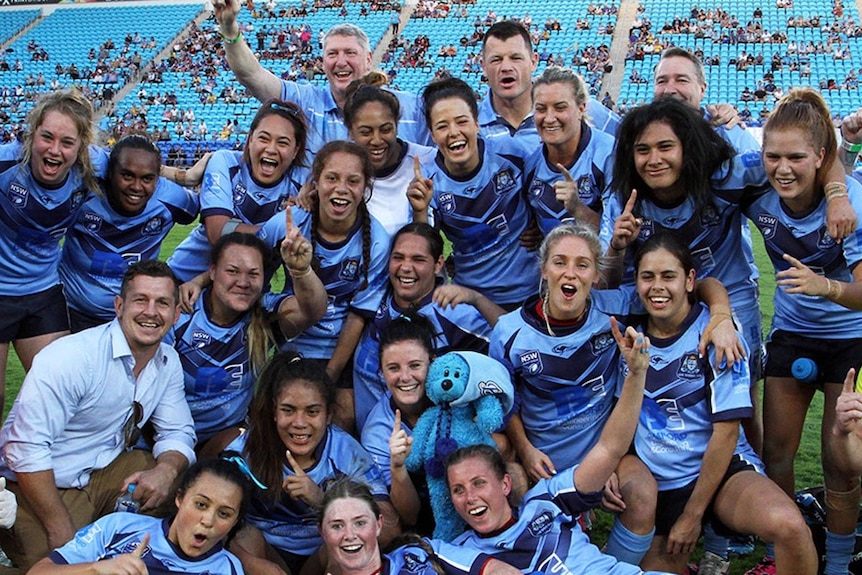 A group of players celebrate winning a rugby league match