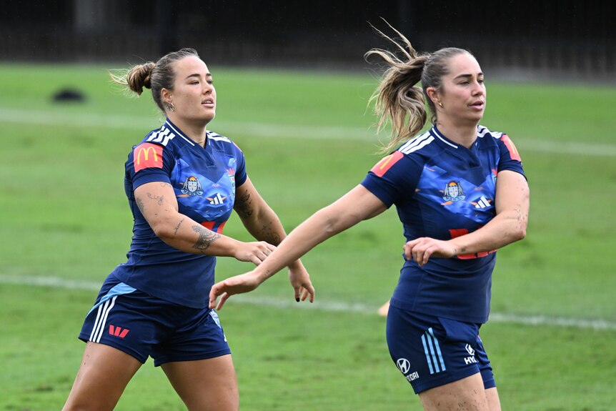Two women warm up before a rugby league training session