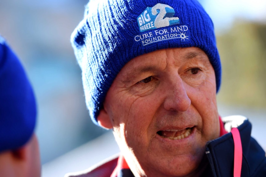 An older man wears a blue beanie with a logo saying "Big Freeze 2: Cure for MND Foundation".