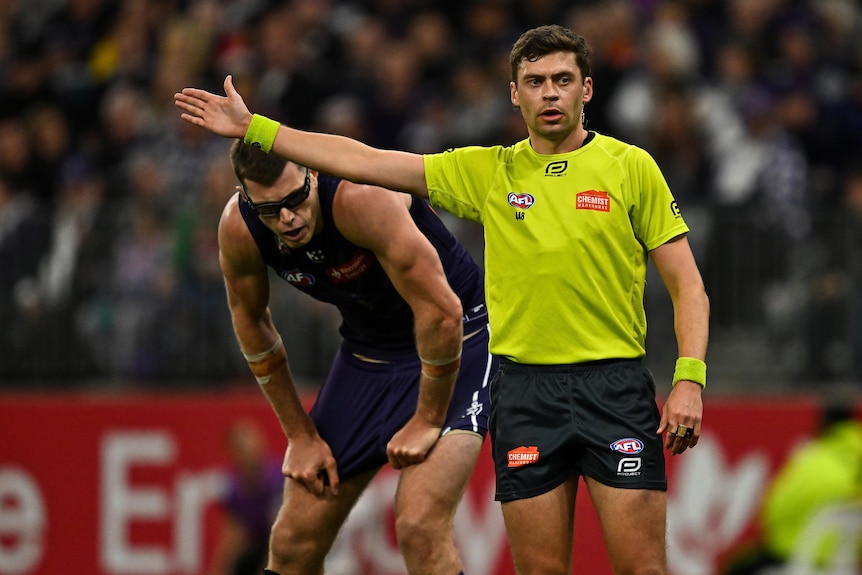 An umpire stands with his arm out