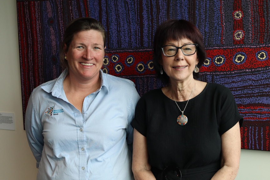 Two women stand next to each other and smile