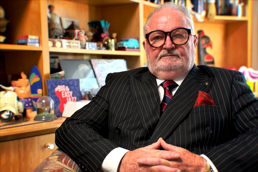 Peter Jess sits in an office, dressed in suit and tie, looking into camera with serious expression.
