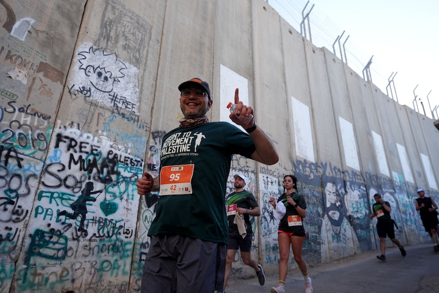 Runners smile as they pass a wall