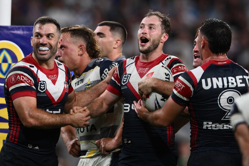 Sam Walker celebrates a try in a rugby league match with two teammates.