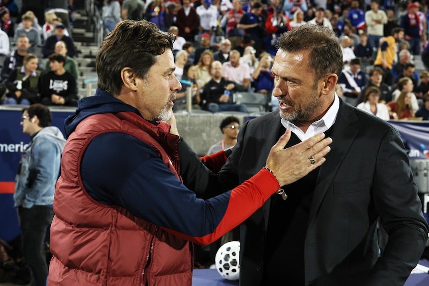 Mauricio and Tony speak to each other on the sidelines of a football match, Mauricio has hand on Tony's chest.