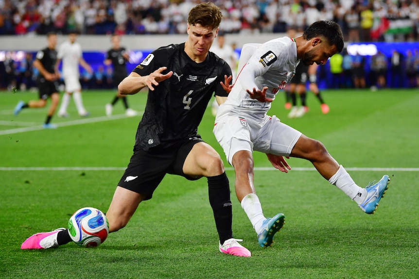 New Zealand's Tyler Bindon and Iran's Mehdi Ghayedi contest for the ball at the 2026 World Cup.