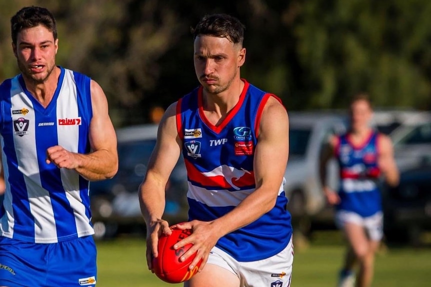 A man in the blue and red football guernsey running with the ball