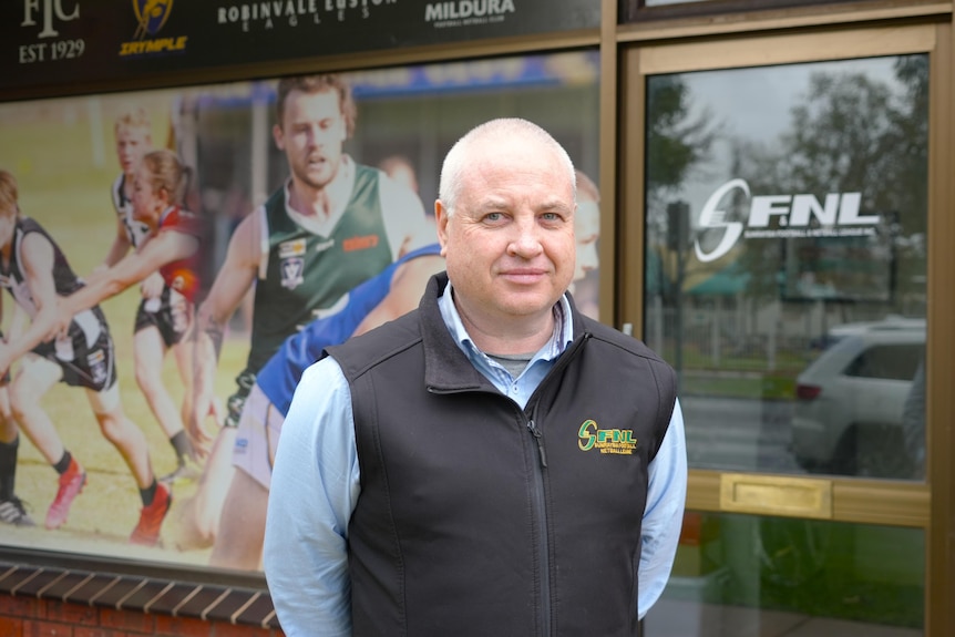 A man smiling at the camera wearing a SFNL vest