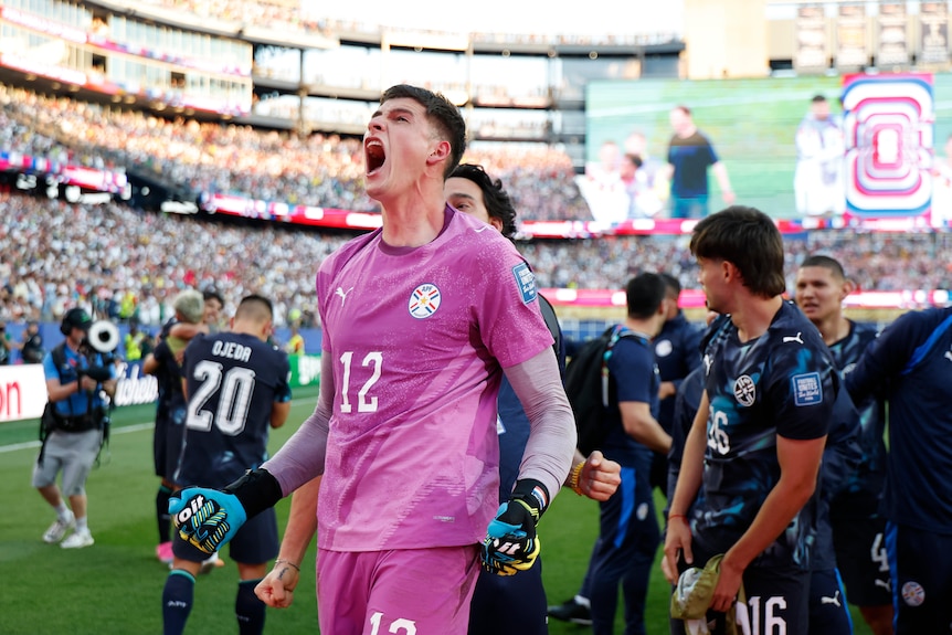 Orlando Gill screams towards the crowd while players celebrate behind him