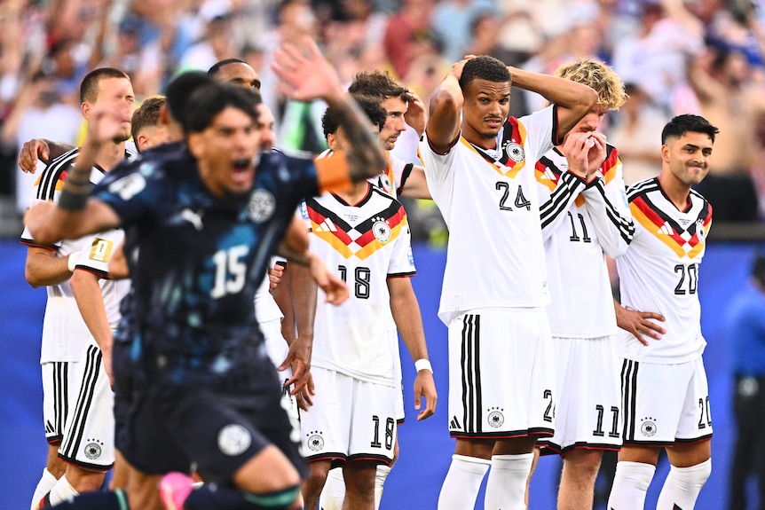 Germany players react as a Paraguay player celebrates in the foreground.