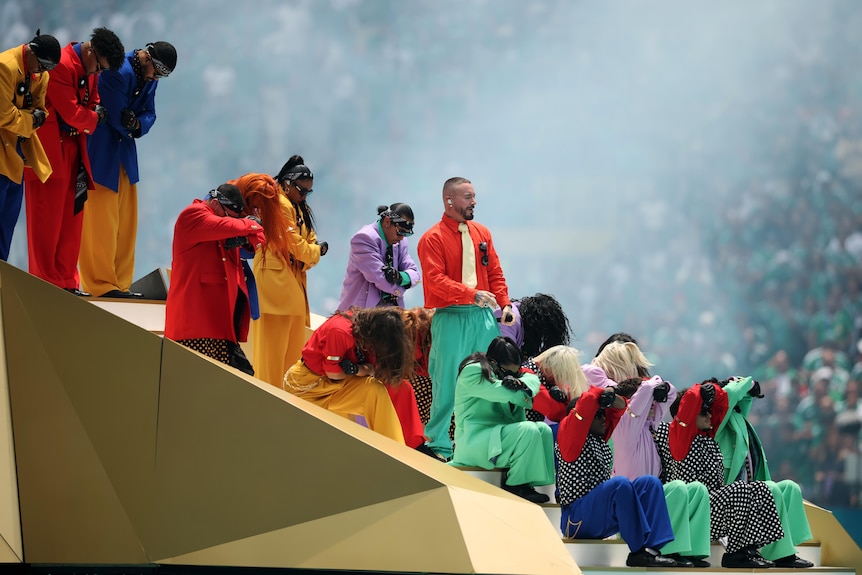 J Balvin performs on steps with dancers in colourful kits
