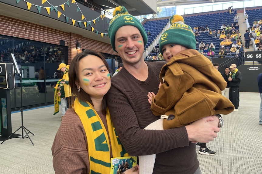 a couple with their child smile at the camera