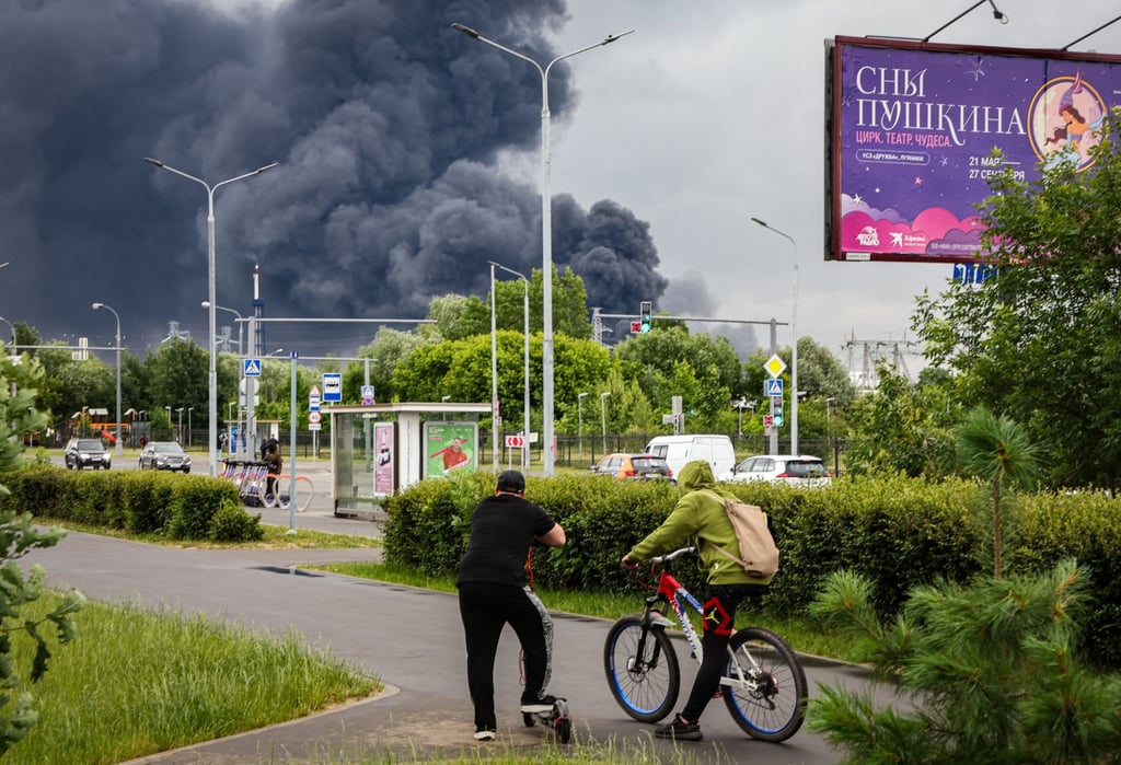 Muscovites watch smoke billowing in the background following a Ukrainian drone attack on Thursday. Photo: EPA