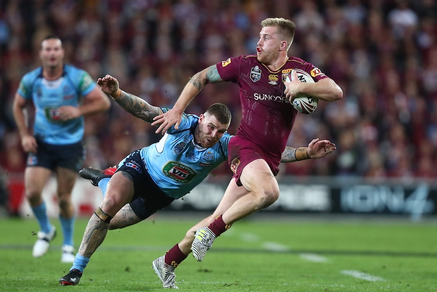 A man runs the ball during a rugby league match