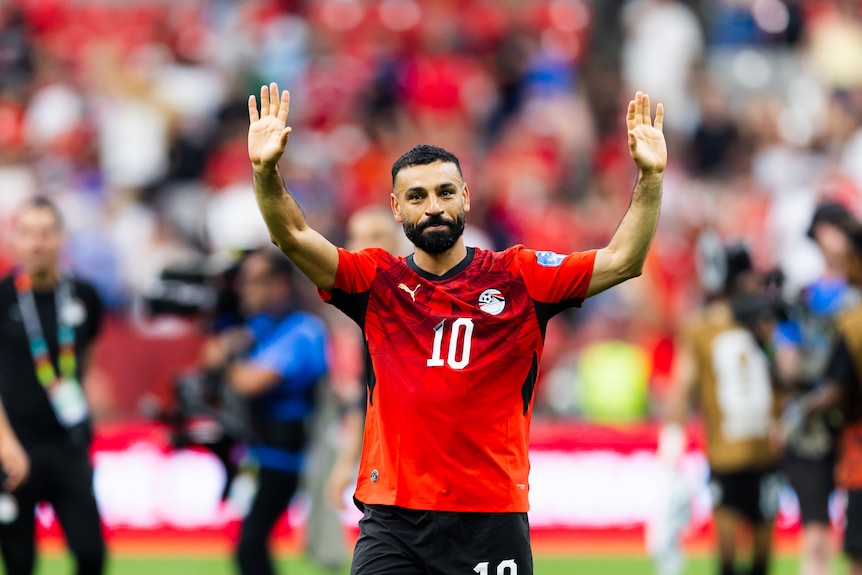 A soccer player in red waves to a crowd