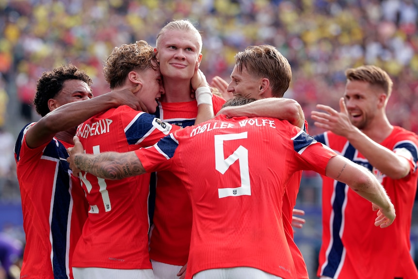 Erling Haaland smirks while he is mobbed by Norway teammates