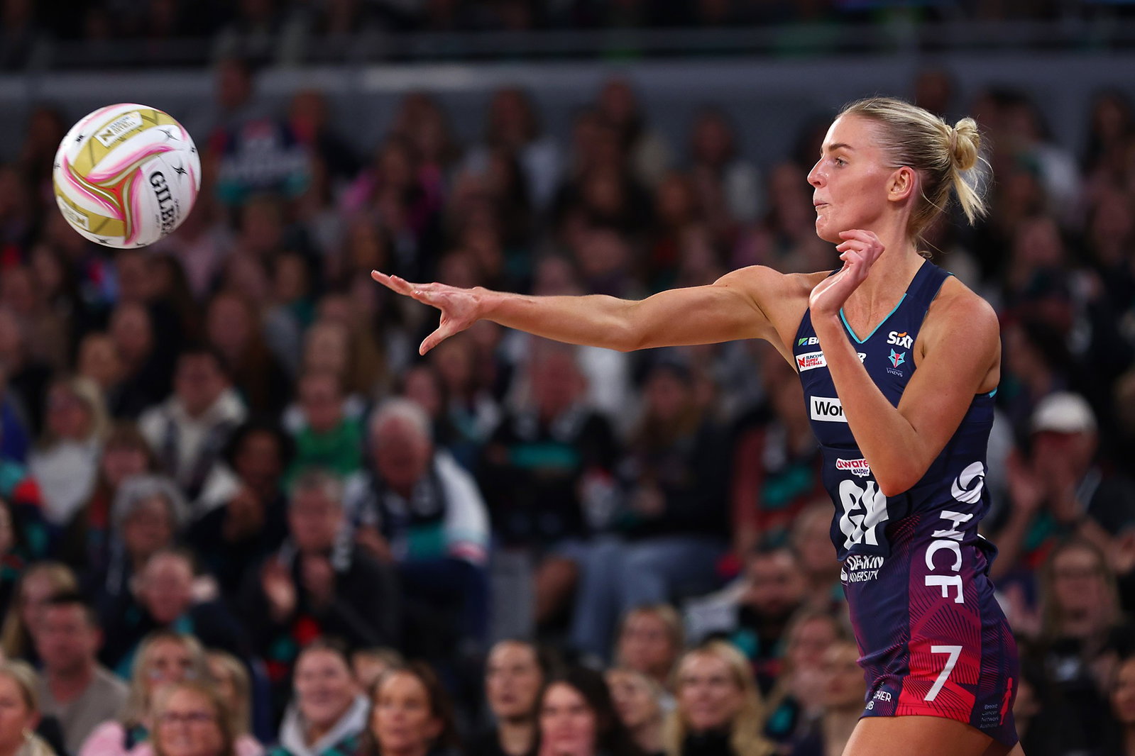 A player stretches her arm out long to pass the ball.