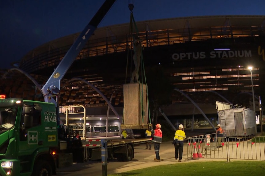 A crane removes the statue of Nicky Winmar.