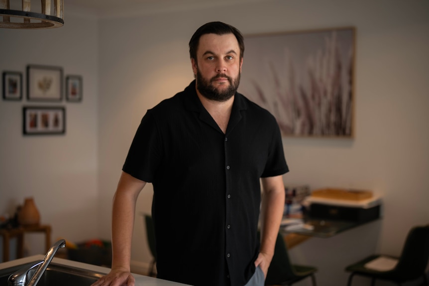 A man standing in his kitchen, looking at the camera.