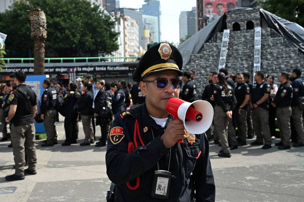 A member of the Secretariat of Citizen Security uses a megaphone to give instructions to personnel evacuated from several buildings in Mexico City after an earthquake on Friday. Photo: AFP A member of the Secretariat of Citizen Security uses a megaphone to give instructions to personnel evacuated from several buildings in Mexico City after an earthquake on Friday. Photo: AFP