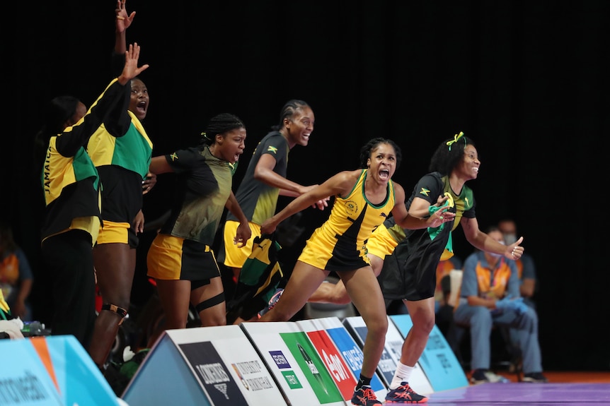 Team members run onto the court from the bench celebrating.