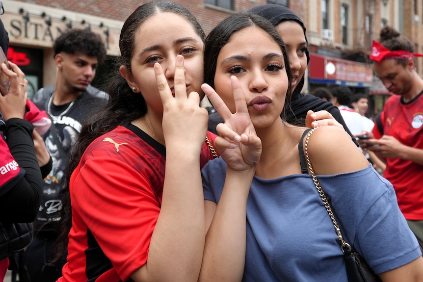 Two young women pose signalling peace signs