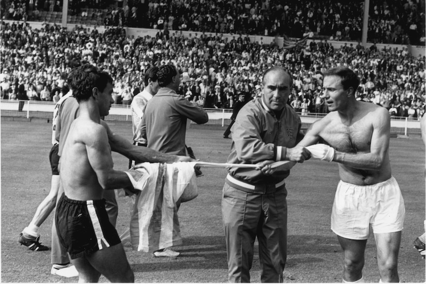 Alf Ramsey pulls at George Cohen's shirt