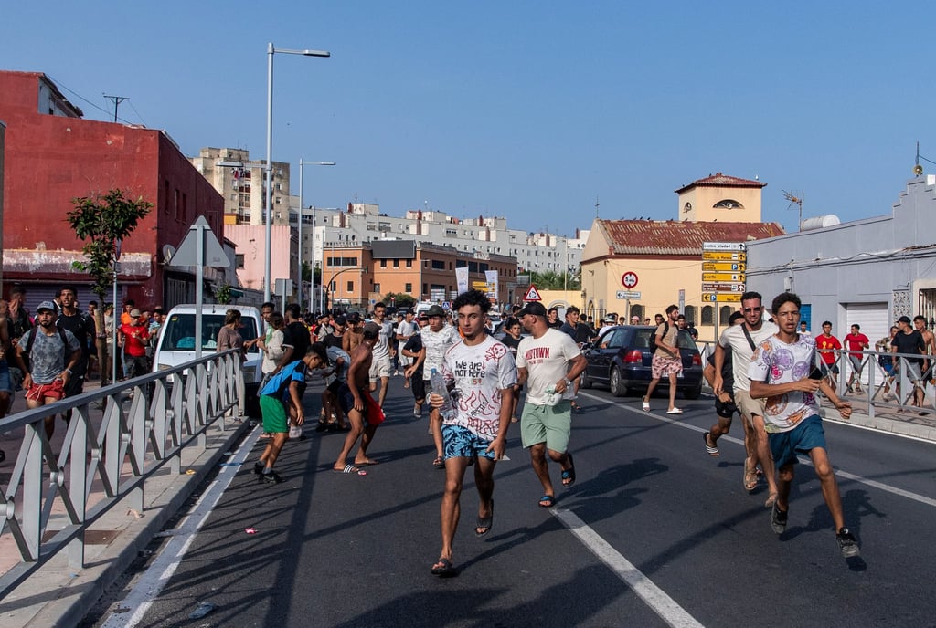 Migrants run from Spanish police after crossing from Morocco into Ceuta on Friday. Photo: AP Migrants run from Spanish police after crossing from Morocco into Ceuta on Friday. Photo: AP