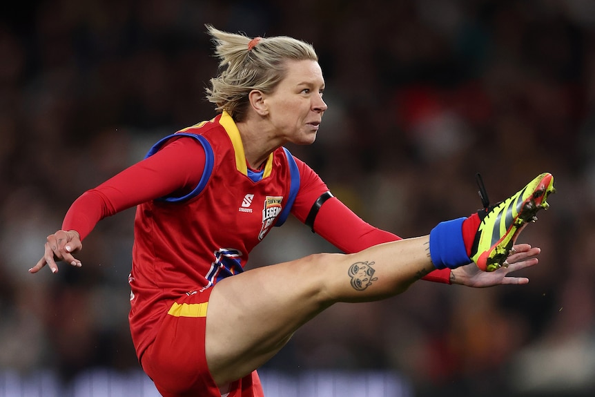 Kate McCarthy kicks a football during an AFL Legends game.