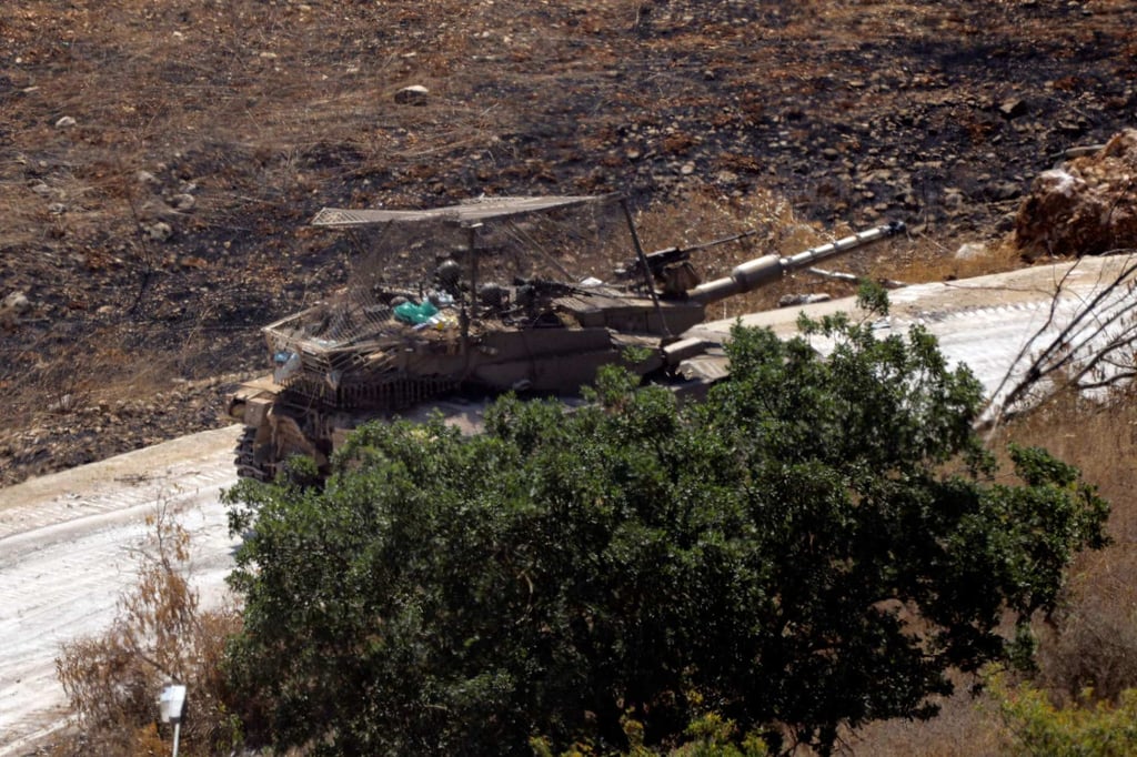 A photograph taken from the Lebanese village of Chaqra shows an Israeli tank rolling along a road through the nearby area of Wadi al-Slouki on Friday. Photo: AFP