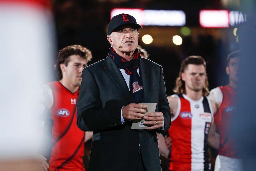 Tim Watson wearing an Essendon cap and hat and speaks