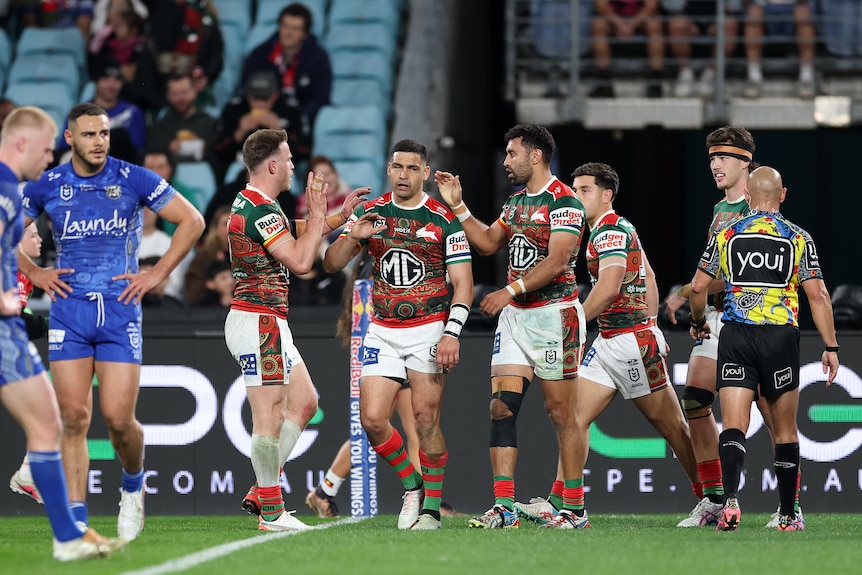 A team celebrates scoring in an NRL match