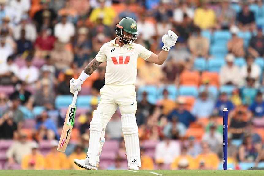A cricketer looks dejected in front of his stumps and with helmet on