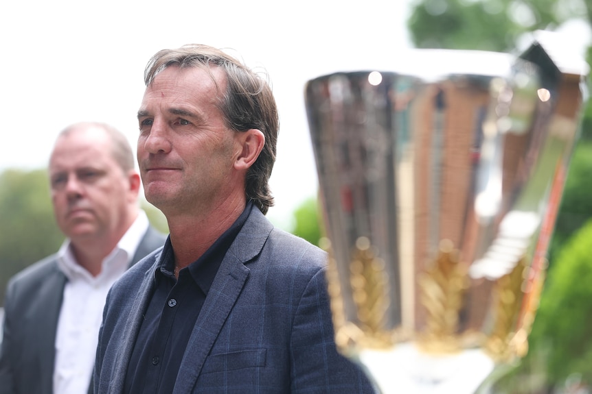 Andrew Dillon standing next to AFL trophy