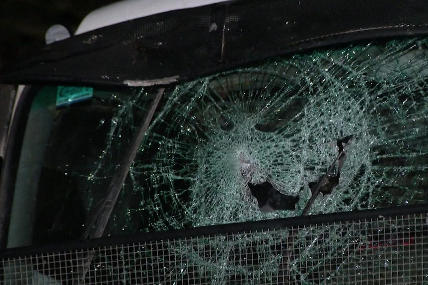 A close-up of a truck windscreen - it is shattered and has a hole on the driver's side.