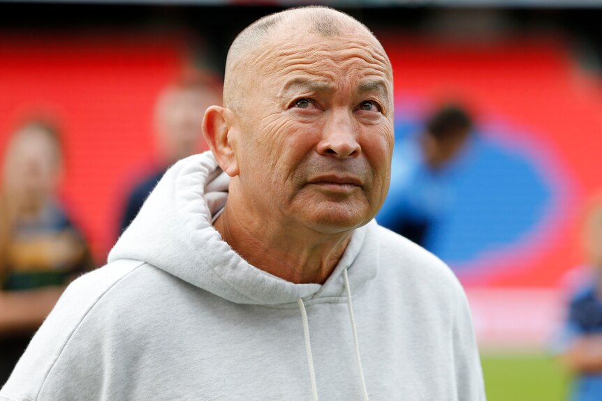 Man in a hooded top standing in an empty stadium, looking skyward