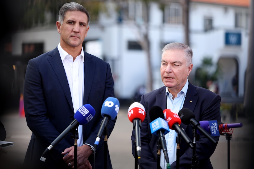 Sydney Swans chief executive Matthew Pavlich and chairman Andrew Pridham speak in front of media microphones.