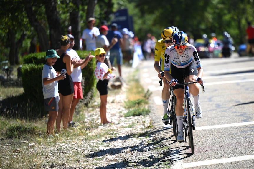 Cyclist Demi Vollering in a race with spectators clapping on the sidelines. 