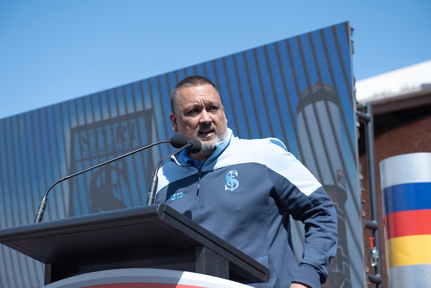 Man wearing blue and sturt football club colours stands on a podium